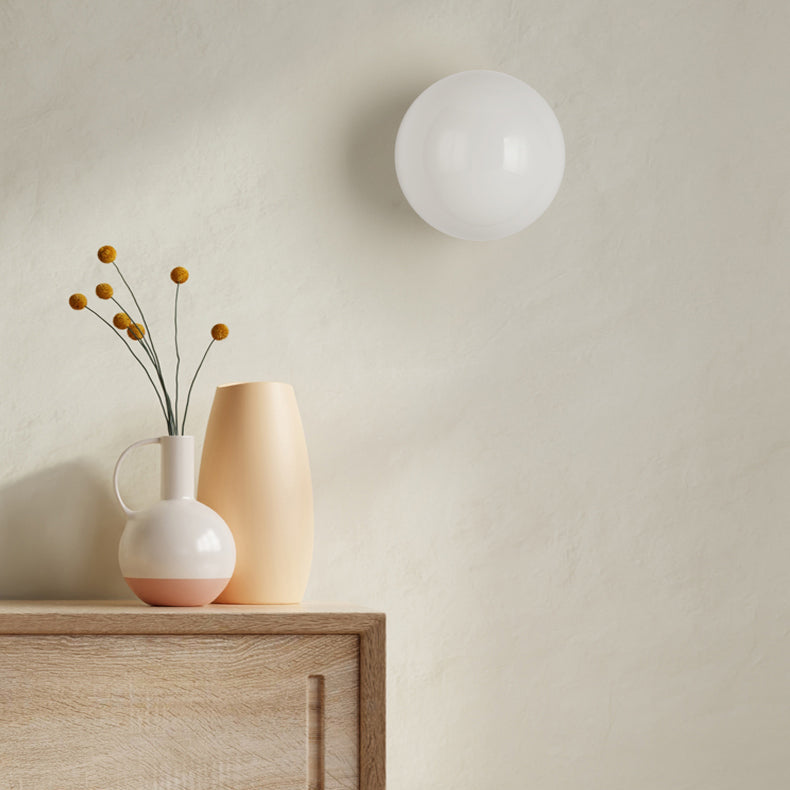 Ausgeschaltete weiße Kugelleuchte an einer Wand über einer Holzkommode mit Vasen und Trockenblumen 6