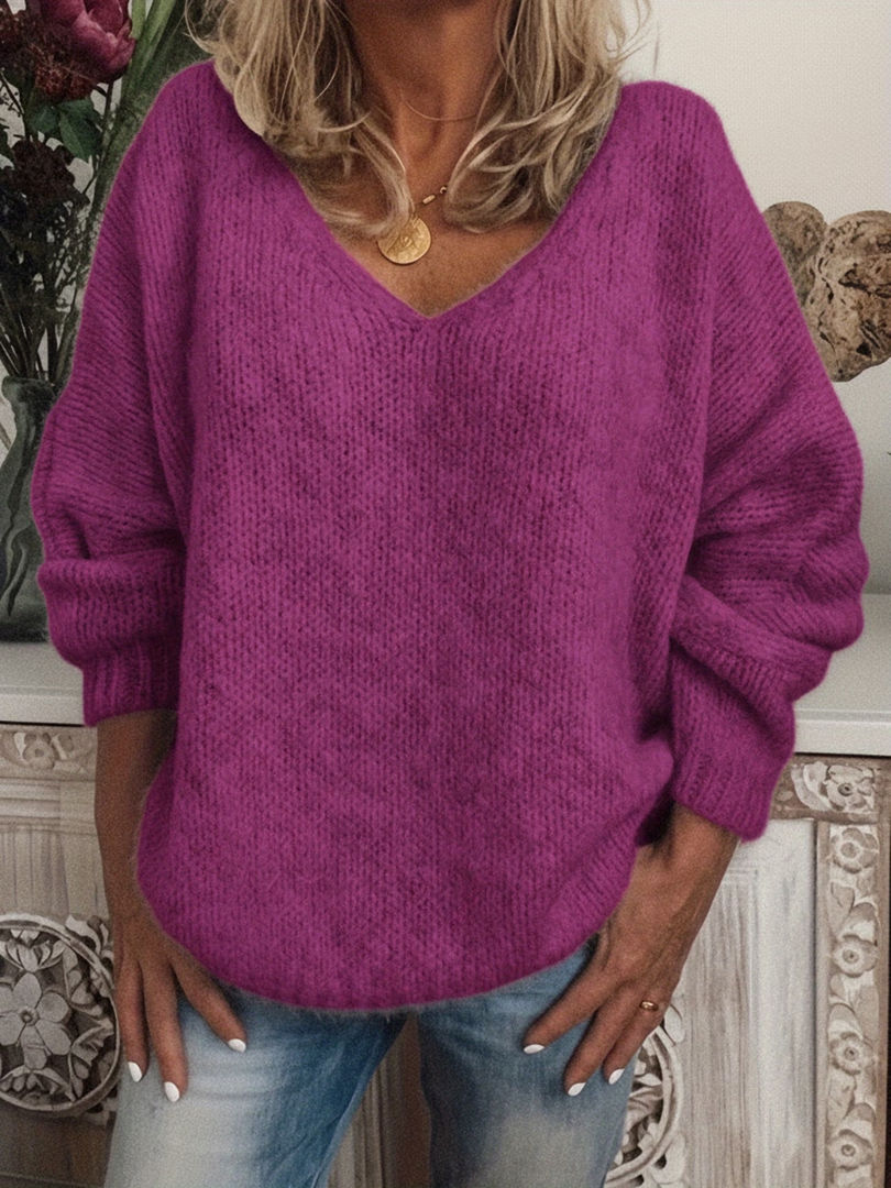 Lockerer Strickpullover mit V-Ausschnitt in kräftigem Violett-Pink, getragen zu Jeans mit goldener Halskette. 6