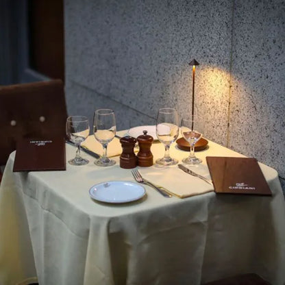 Eleganter Restauranttisch mit Weingläsern, Menüs und Tischlampe, ideal für romantisches Abendessen.