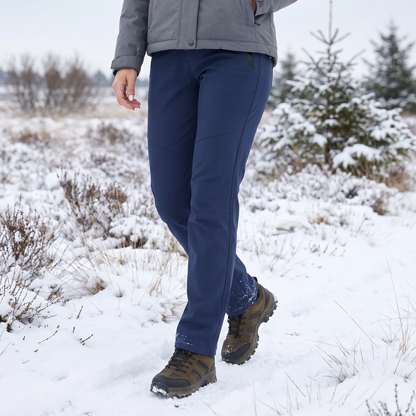 Frau in marineblauer Hose und grauer Jacke beim Spaziergang durch eine verschneite Heidelandschaft 1