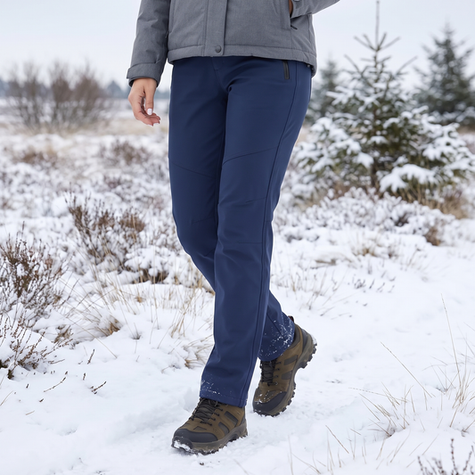 Frau in marineblauer Hose und grauer Jacke beim Spaziergang durch eine verschneite Heidelandschaft 1
