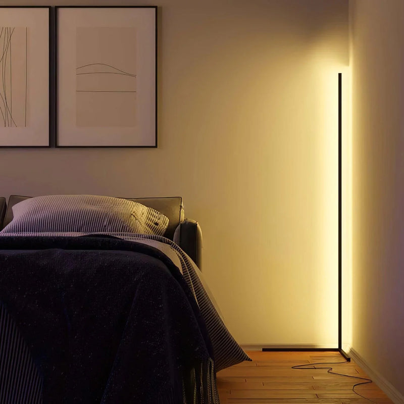 Stehlampe in gelblichem Licht in der Zimmerecke neben einem Bett, daneben zwei gerahmte Bilder 4