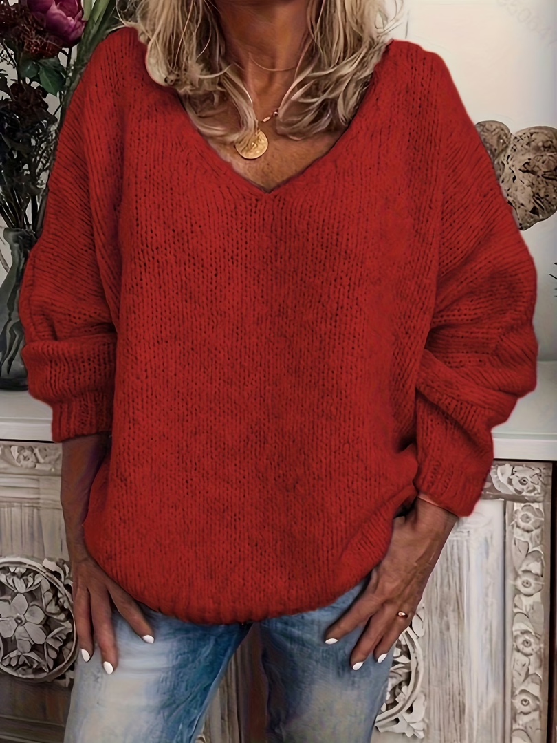 Frau trägt den weit geschnittenen V-Ausschnitt-Pullover in leuchtendem Rot, grobe Strickstruktur, dazu Jeans. 5