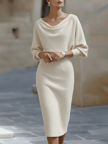 Frontansicht: Model in cremefarbenem Strickkleid mit weichem Wasserfallausschnitt, Fledermausärmeln und schmal geschnittenem Rock bis zur Wade. 3