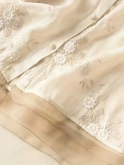 Beige Seidenstoff mit floraler Stickerei, luxuriöses Material für elegante Mode und Dekoration.