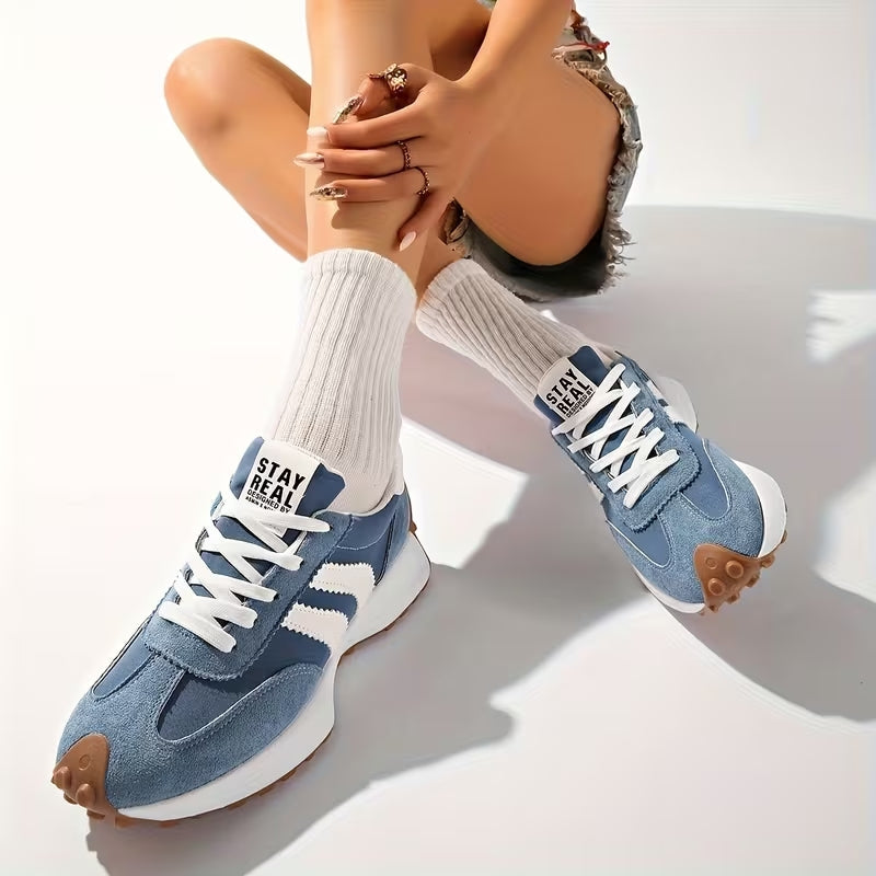 Model sitzt mit überkreuzten Beinen und trägt blaue Wildleder-Sneaker mit weißen Rippensocken 9