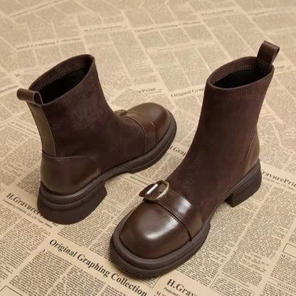 Braune Wildlederstiefel mit Zuglasche an der Ferse, Lederkappe, goldfarbener Schnalle und Blockabsatz, Detail.