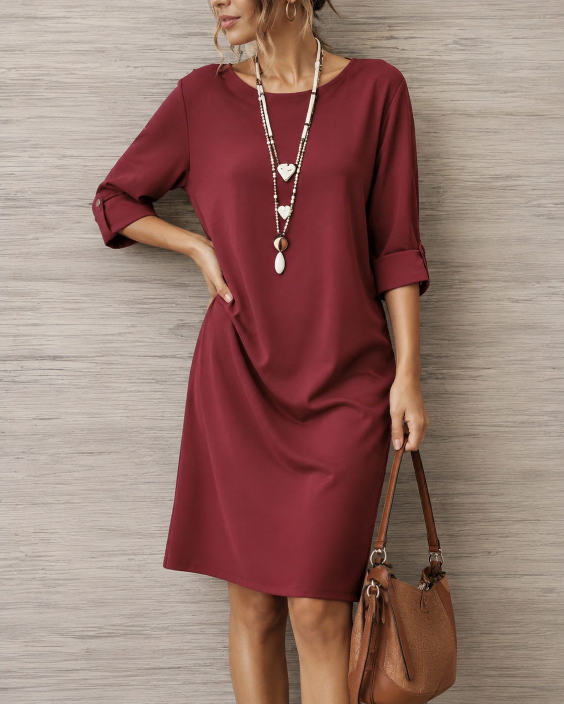 Weinrotes Kleid mit Rundhals und gekrempelten Ärmeln, Nahaufnahme mit Herzkette und brauner Umhängetasche 6