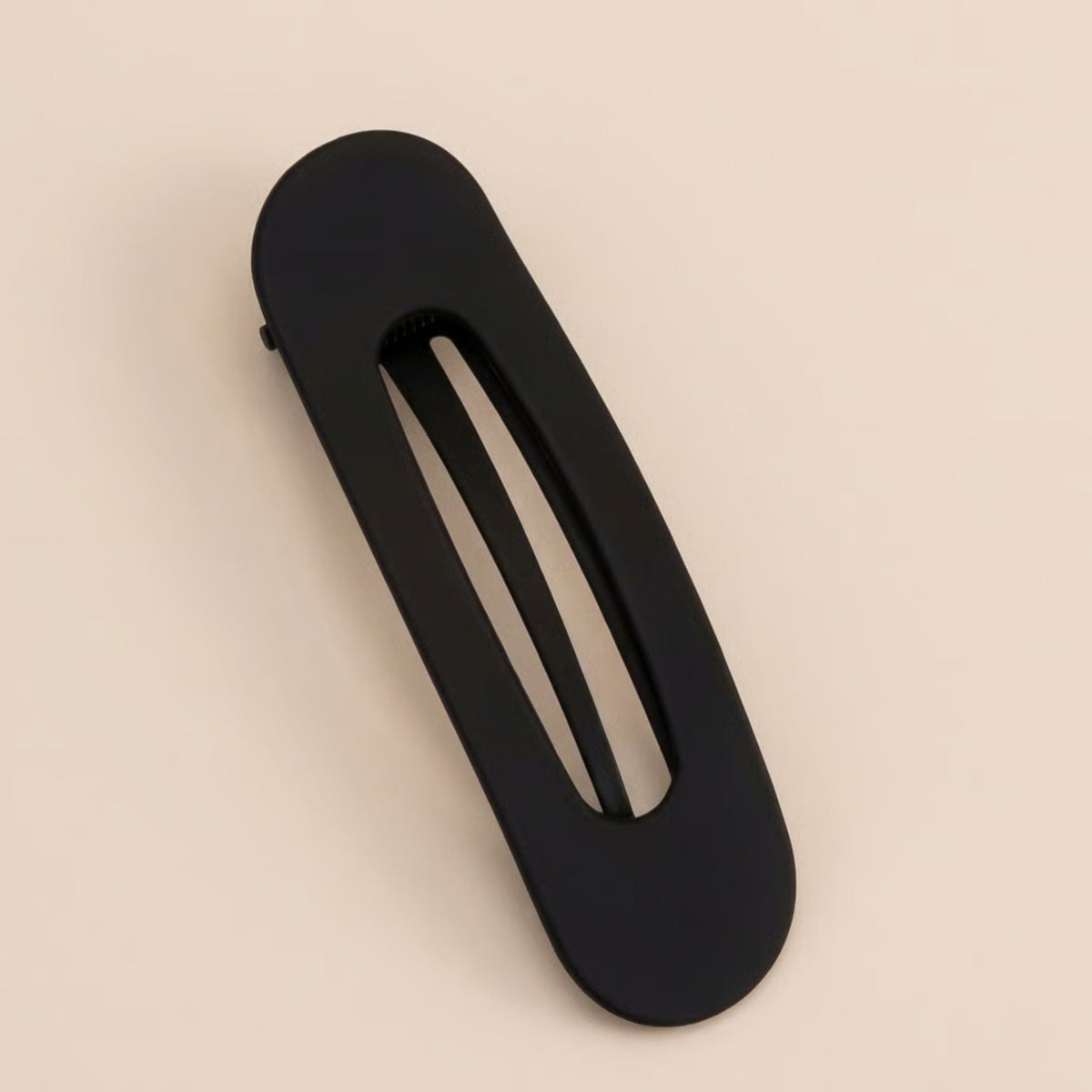 Schwarze matte Haarspange mit länglicher Aussparung von oben vor beigem Hintergrund 5