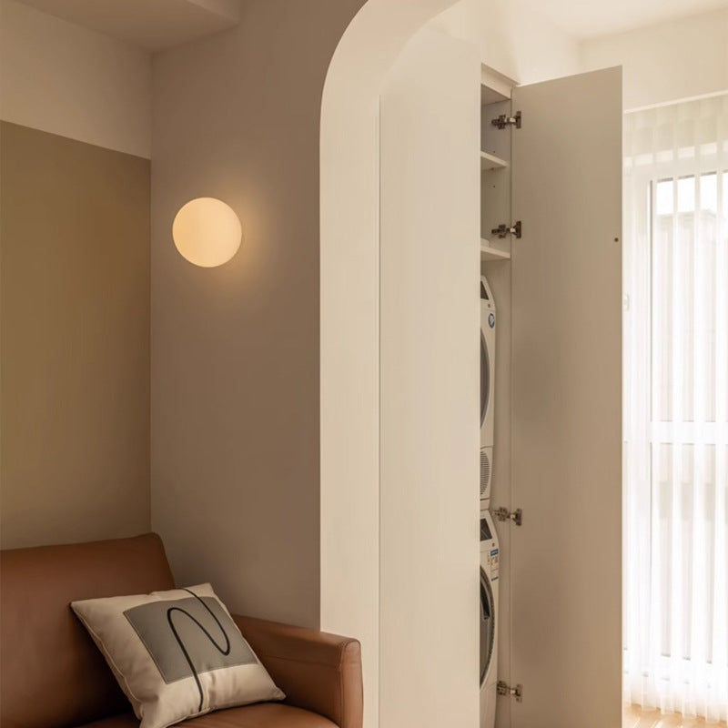 Kugelleuchte an der Wand neben einem Rundbogen, darunter ein Sofa mit Kissen in einer Ecke 4