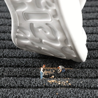 Detail der Fußmatte mit grauer Schlingenoberfläche und Streifenmuster.