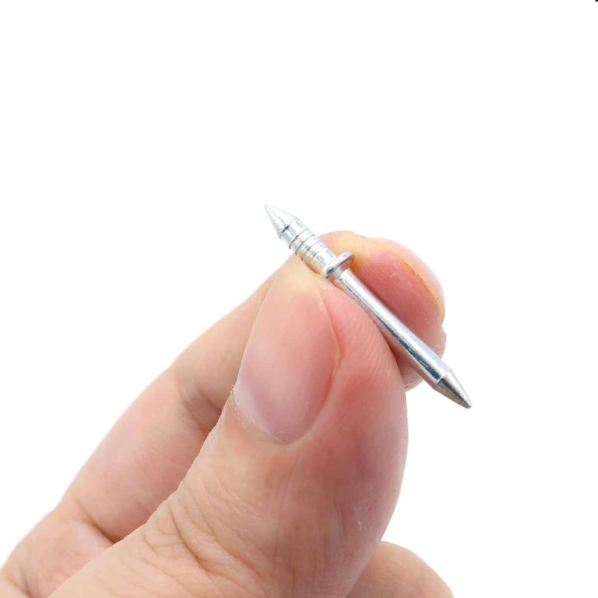 Ein einzelner doppelseitiger Nagel aus Metall zwischen zwei Fingern.