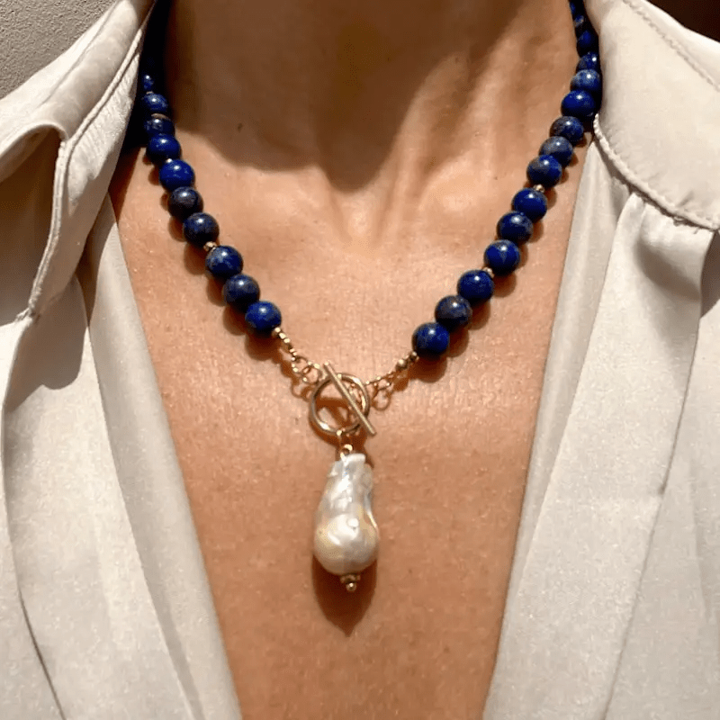 Getragen am Hals, mittig der Knebelverschluss mit hängender Barockperle vor heller Bluse 4