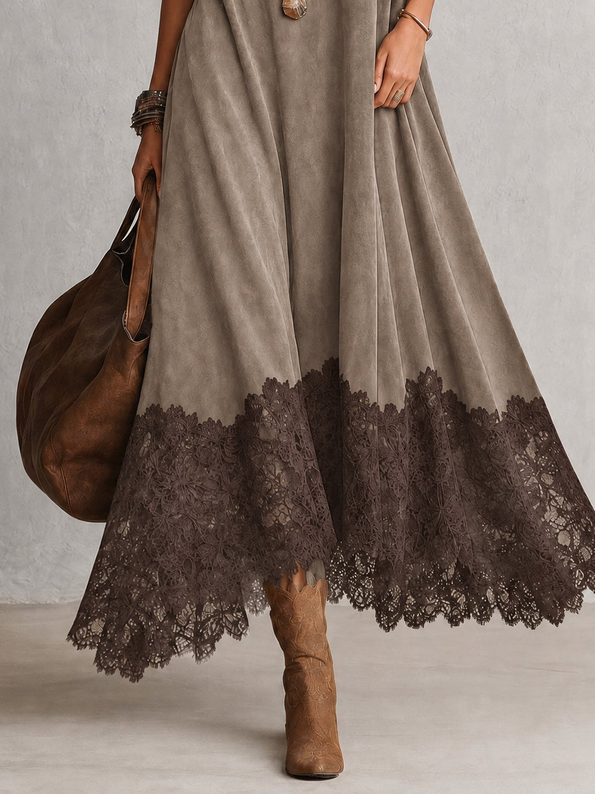 Nahaufnahme des dunklen Spitzensaums am graubeigen Kleid, dazu Stiefel und Lederbeutel 14