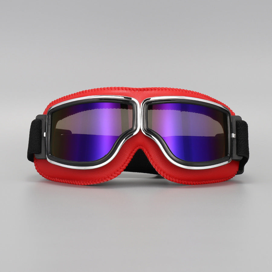 Brille mit rotem Lederrand und Chromrahmen, die Gläser schimmern verspiegelt in Violett und Blau. 12