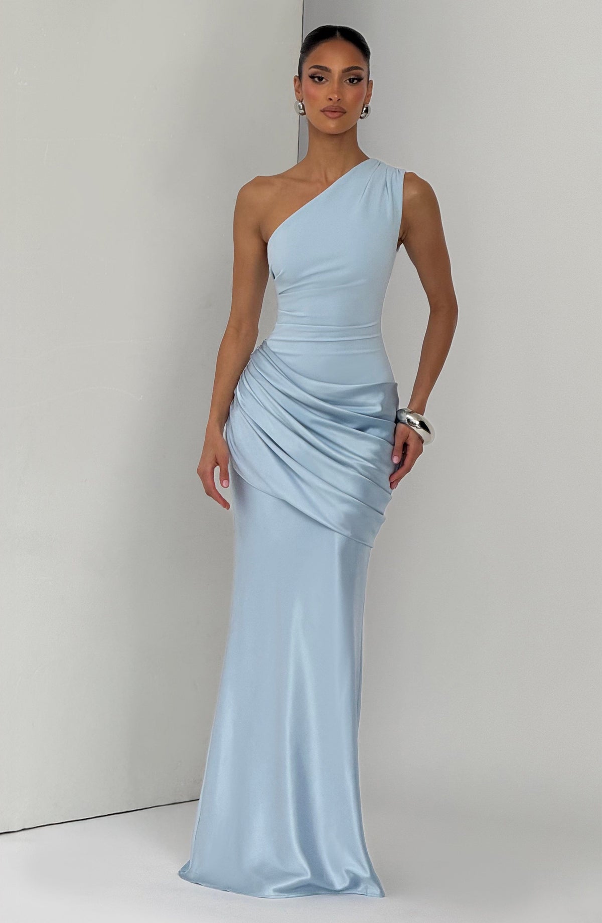 Hellblaues Maxikleid aus Satin, Frontansicht am Model vor hellgrauer Wand.