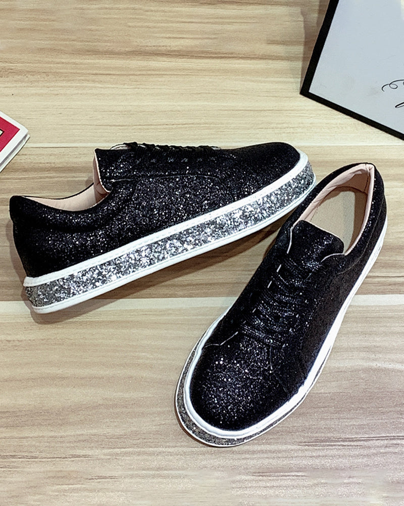 Schwarze Glitzersneaker mit silberner Sohle auf Holzboden, modische Damen-Sportschuhe.