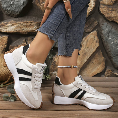 Weiß-graue Sneaker mit schwarzen Streifen, getragen zu Jeans vor einer Steinmauer 5