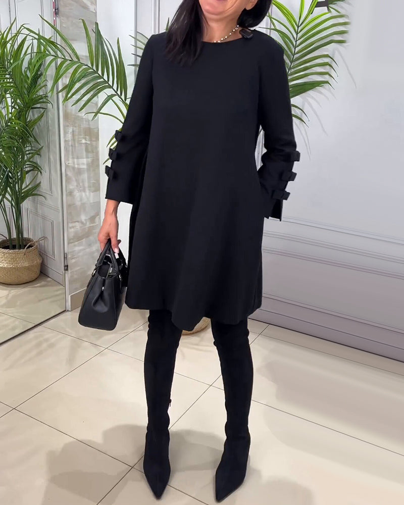 Schwarzes Damenkleid mit langen Ärmeln, elegantes Design, schwarze Stiefel, Handtasche.