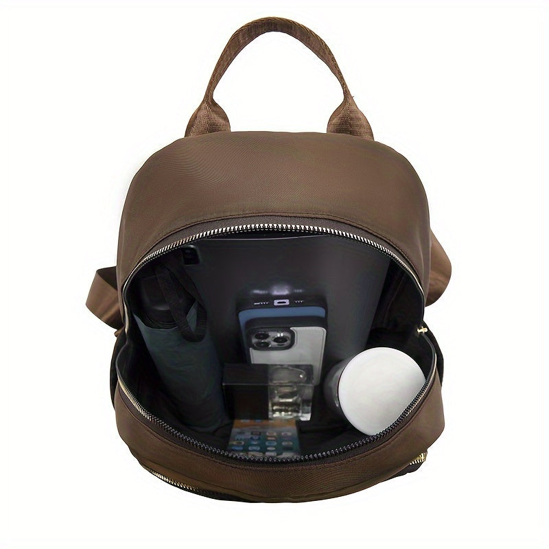 Geöffnetes Hauptfach des braunen Rucksacks, gefüllt mit Schirm, Smartphone, Parfümflasche und Dose 18