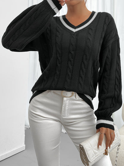 Frau in schwarzem Strickpullover mit V-Ausschnitt und weißen Jeans, hält weiße Clutch.