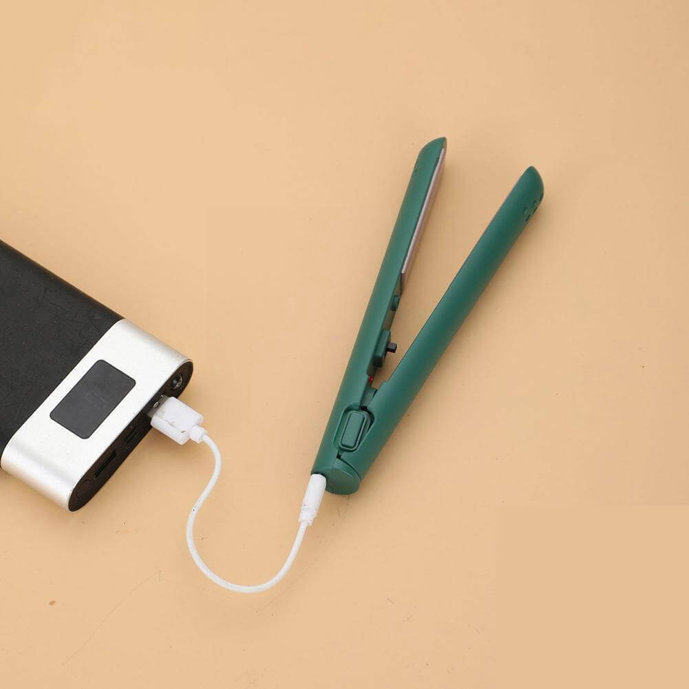 Grüner Mini-Glätter geöffnet, per weißem USB-Kabel an eine Powerbank angeschlossen, auf beigem Untergrund. 1
