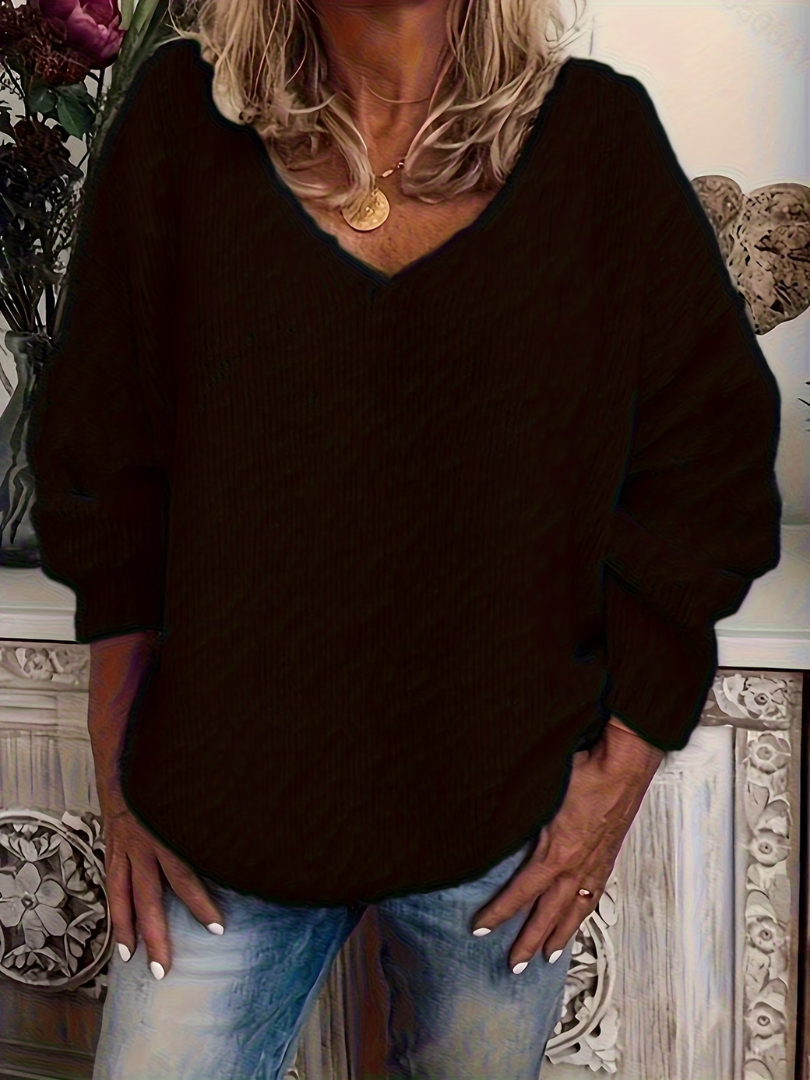 Frau im lockeren V-Ausschnitt-Pullover in Schwarz, fein gerippte Strickstruktur, kombiniert mit heller Jeans. 3