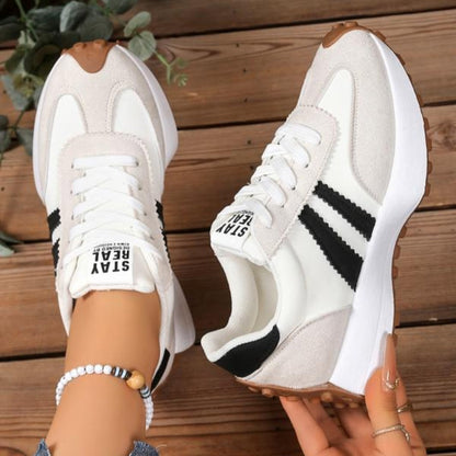 Weiße Sneaker mit schwarzen Streifen und beigem Wildleder, ein Schuh getragen, der andere in der Hand 10