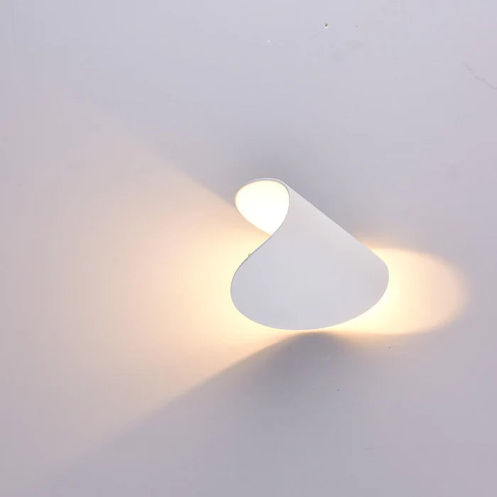 Weiße Wandleuchte, seitlich gedreht, mit warmem Licht in zwei Richtungen an eine helle Wand.