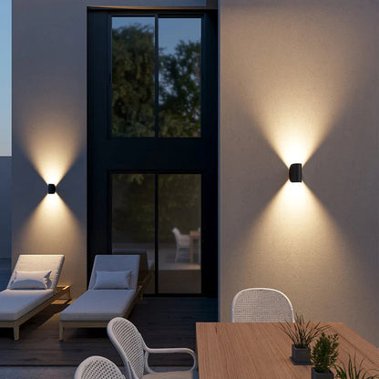 Schwarze Wandleuchten mit Licht nach oben und unten an der Terrassenwand am Abend.