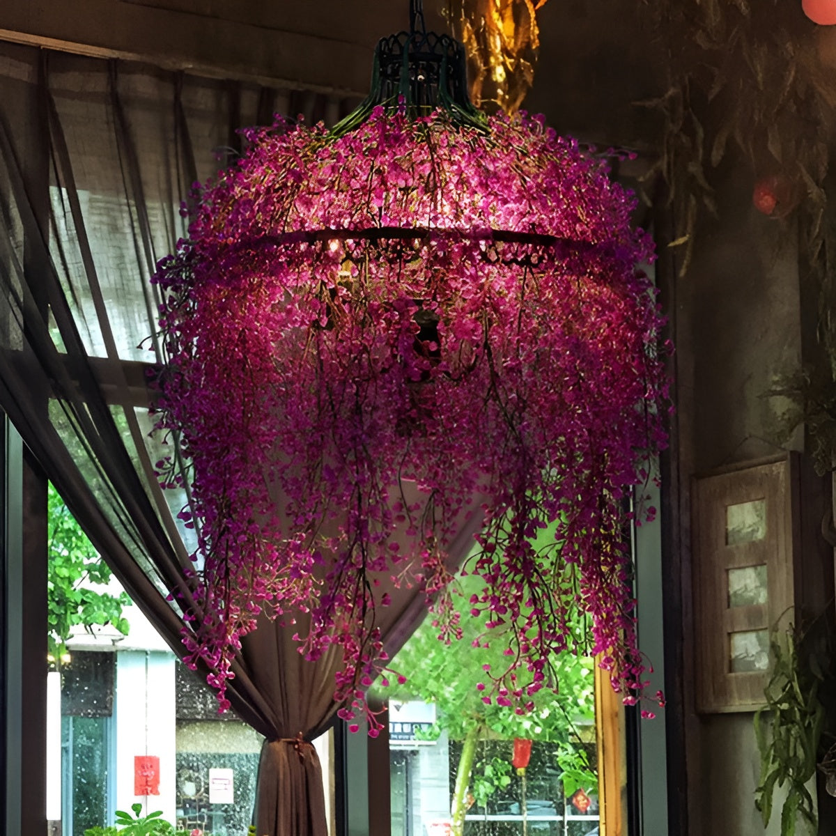 Leuchte mit dichten pinkvioletten Blütenranken, die vor einem Fenster mit Vorhang im Gastraum hängt 5