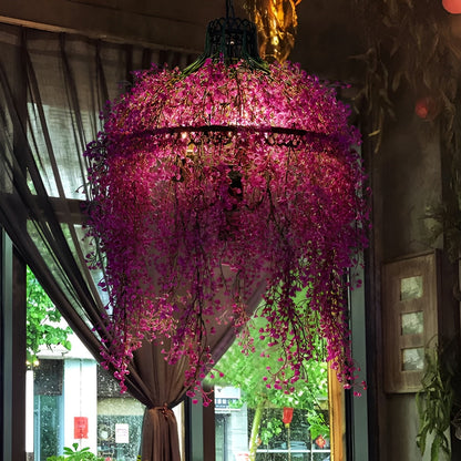 Leuchte mit dichten pinkvioletten Blütenranken, die vor einem Fenster mit Vorhang im Gastraum hängt 5