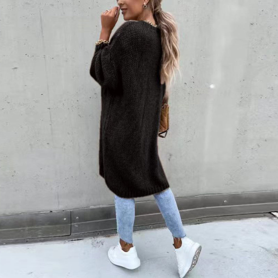 Frau in schwarzem Strickpullover, hellblauer Jeans und weißen Sneakers, lässiger Herbstlook.