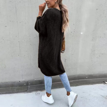Frau in schwarzem Strickpullover, hellblauer Jeans und weißen Sneakers, lässiger Herbstlook.