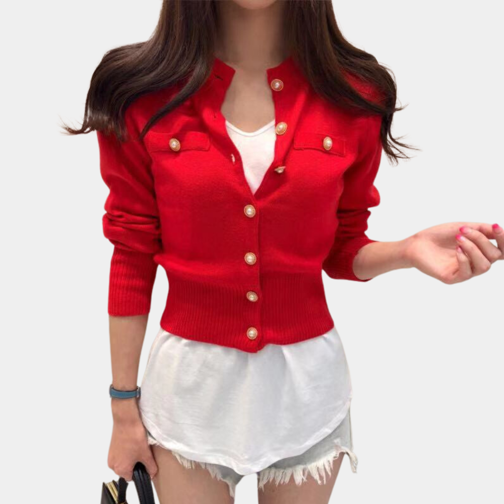 Frau in roter Strickjacke mit goldenen Knöpfen, weißem T-Shirt und Jeansshorts.