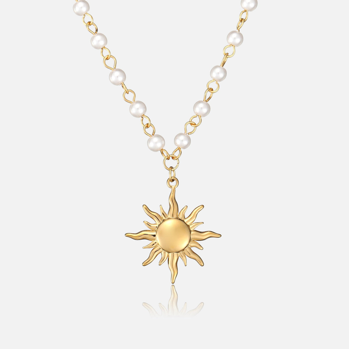 Frontansicht der Halskette mit goldenem Sonnenanhänger an einer Kette aus kleinen weißen Perlen und goldfarbenen Gliedern auf hellem Hintergrund. 1