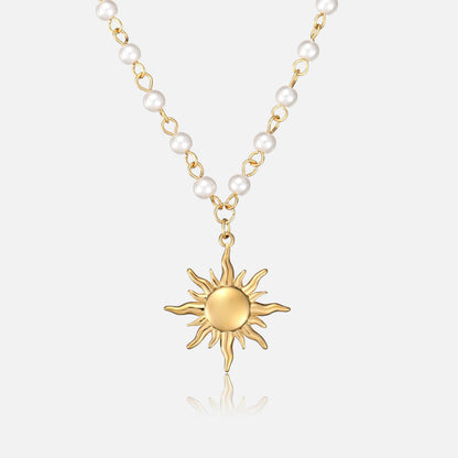 Frontansicht der Halskette mit goldenem Sonnenanhänger an einer Kette aus kleinen weißen Perlen und goldfarbenen Gliedern auf hellem Hintergrund. 1