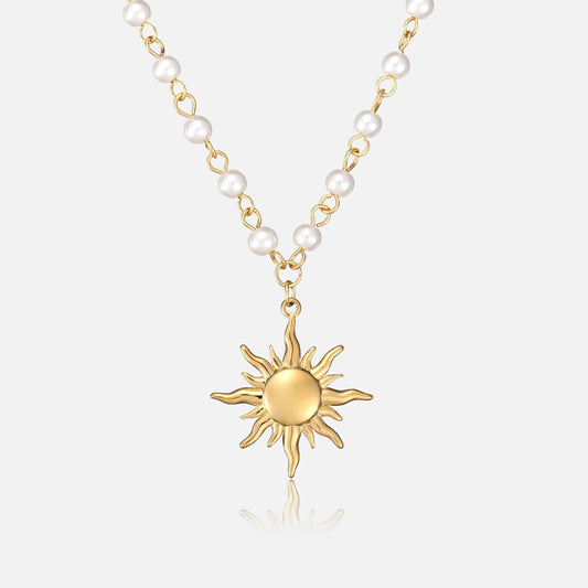 Frontansicht der Halskette mit goldenem Sonnenanhänger an einer Kette aus kleinen weißen Perlen und goldfarbenen Gliedern auf hellem Hintergrund. 1
