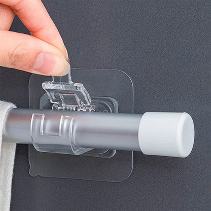 Detail der transparenten Klebehalterung, deren Federclip eine Stange mit weißer Endkappe und ein Tuch hält.