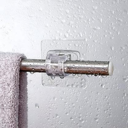 Detail einer transparenten Klebehalterung an einer nassen Duschwand mit Metallstange und violettem Handtuch.