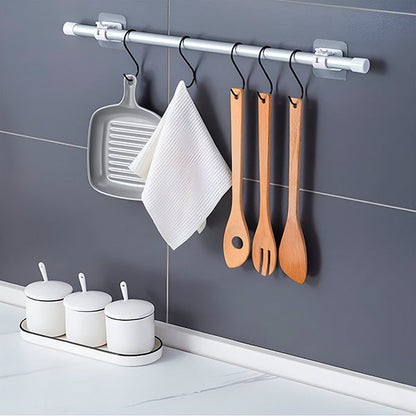 Detail einer Küchenwand mit Stange an zwei Halterungen und S-Haken mit Grillpfanne, Geschirrtuch und Holzbesteck.