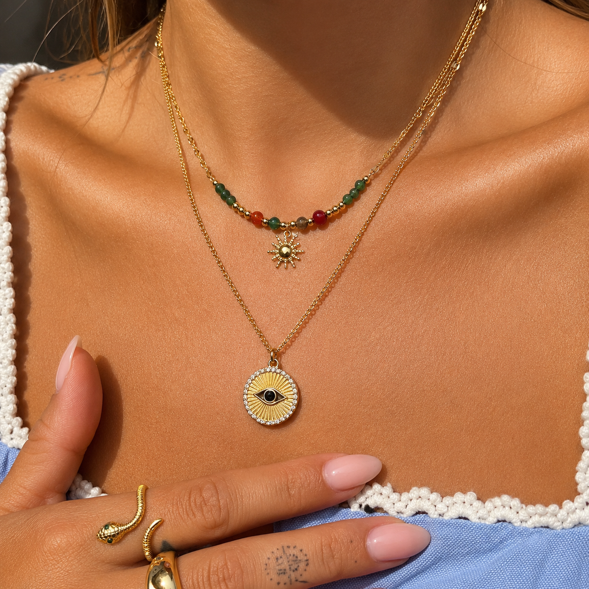 Frau trägt die Perlenkette mit Sonnenanhänger zusammen mit einer zweiten goldenen Kette mit rundem Augen-Medaillon 3