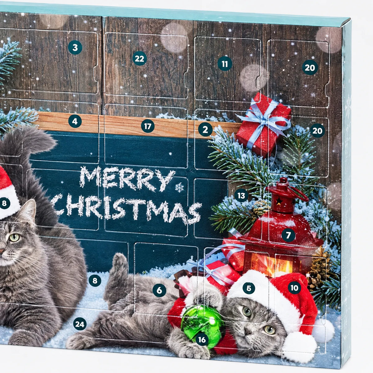 Nahaufnahme der Kalenderfront mit nummerierten Türchen, Tafel, Tannenzweigen, Laterne und zwei grauen Katzen mit Weihnachtsmützen. 3