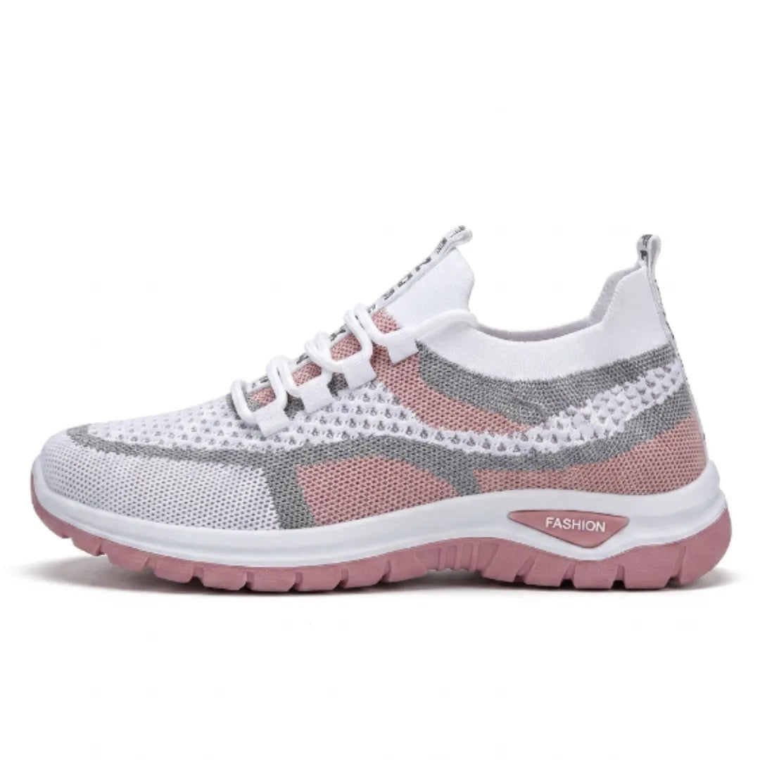 Seitenansicht eines weißen Mesh-Sneakers mit rosa Einsätzen, grauen Streifen und rosafarbener Sohle auf hellem Hintergrund.