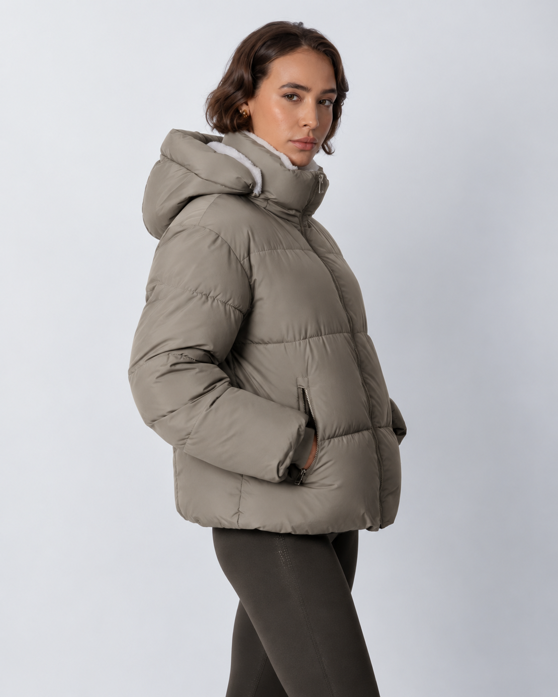 Seitenansicht der graubeigen Steppjacke mit Kapuze, Reißverschlusstasche und Bündchen am Ärmel 19