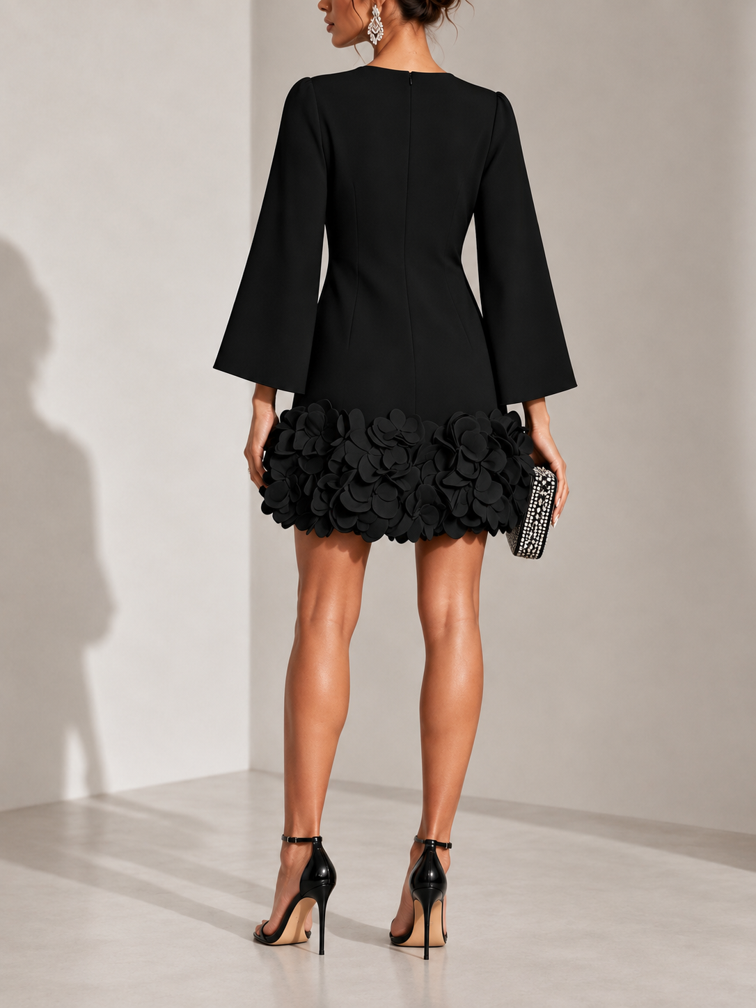Schwarzes kurzes Kleid von hinten mit Reißverschluss, ausgestellten Ärmeln und 3D-Blüten am Saum.