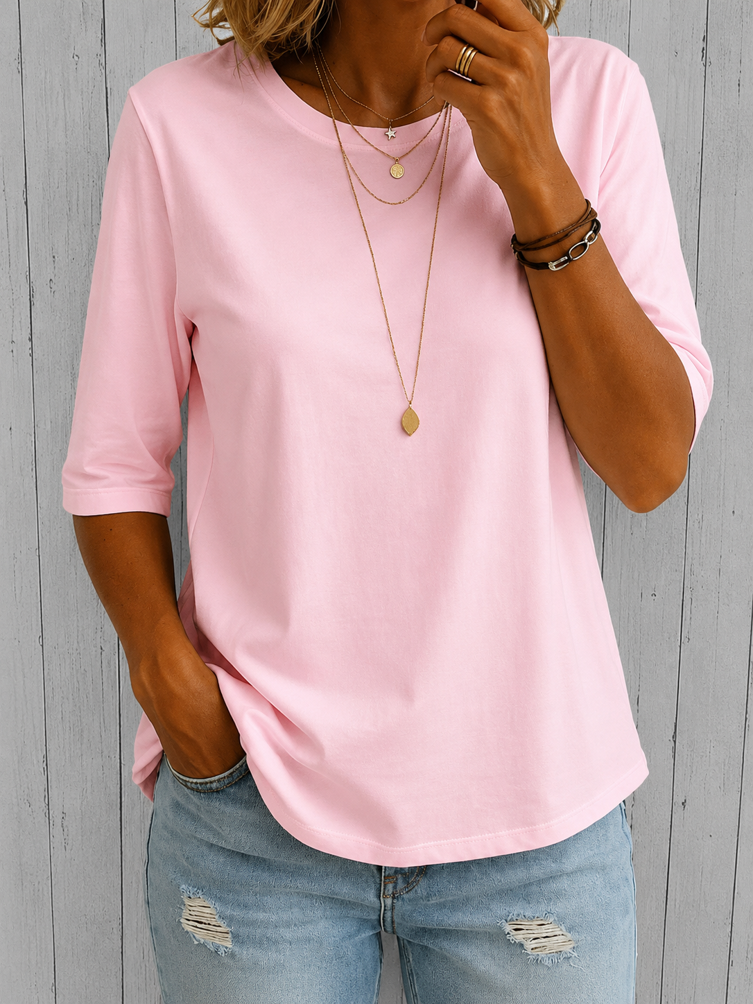 Rosa Halbarm-Shirt mit Rundhals, Frontansicht vor Holzwand.