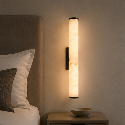 Warm leuchtende Wandleuchte mit Marmorschirm über einem Holznachttisch