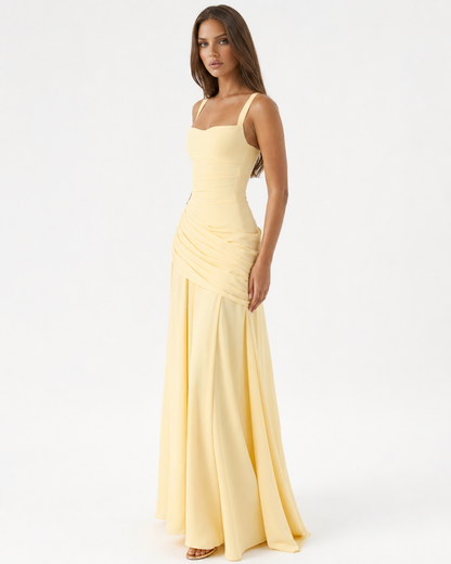 Das gelbe Maxikleid in seitlicher Dreiviertelansicht am Model, mit gerafftem Drapé an der Hüfte und weit fließendem Rock. 2