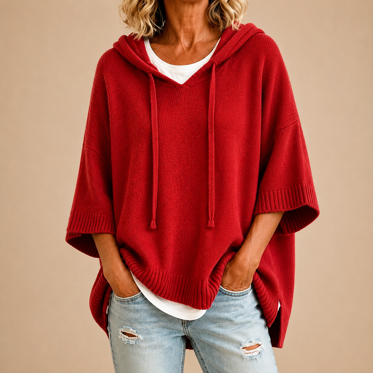 Roter Strickponcho mit Kapuze und seitlichen Schlitzen am Saum, Vorderansicht.